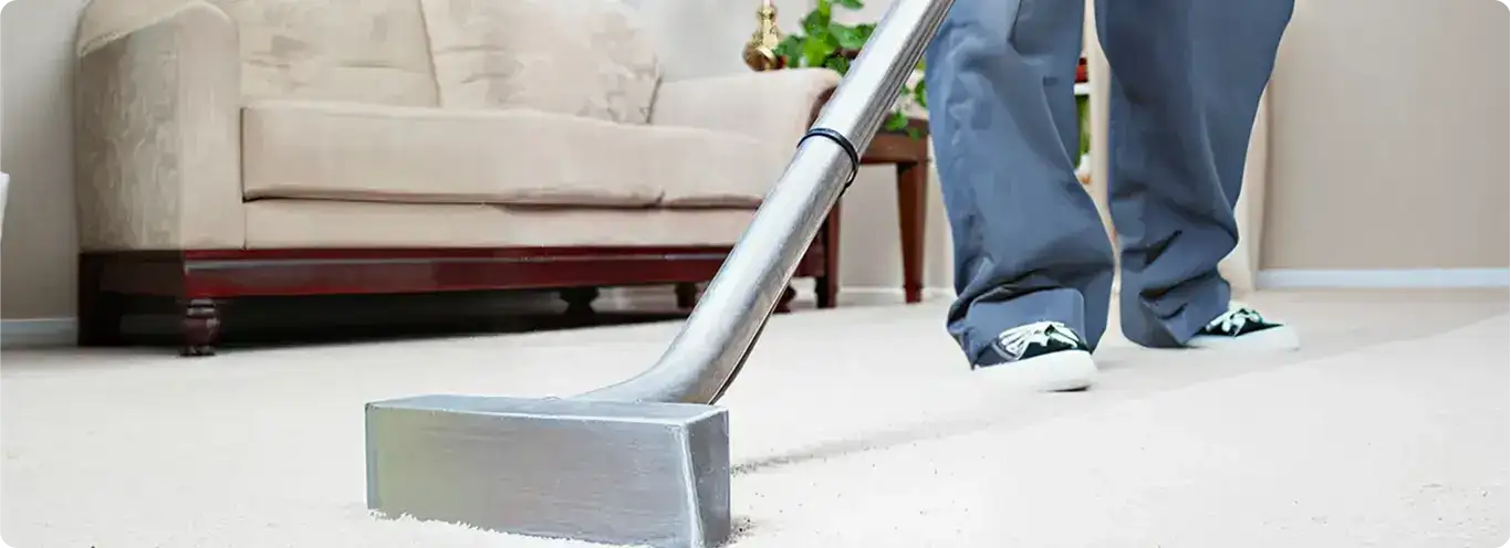 Carpet cleaning technician using a hot-water extraction wand on a light-colored carpet in a living room, Sacramento, CA.