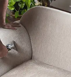 Professional upholstery cleaner deep-cleaning a fabric sofa with a handheld extraction tool and hose Sacramento, CA.